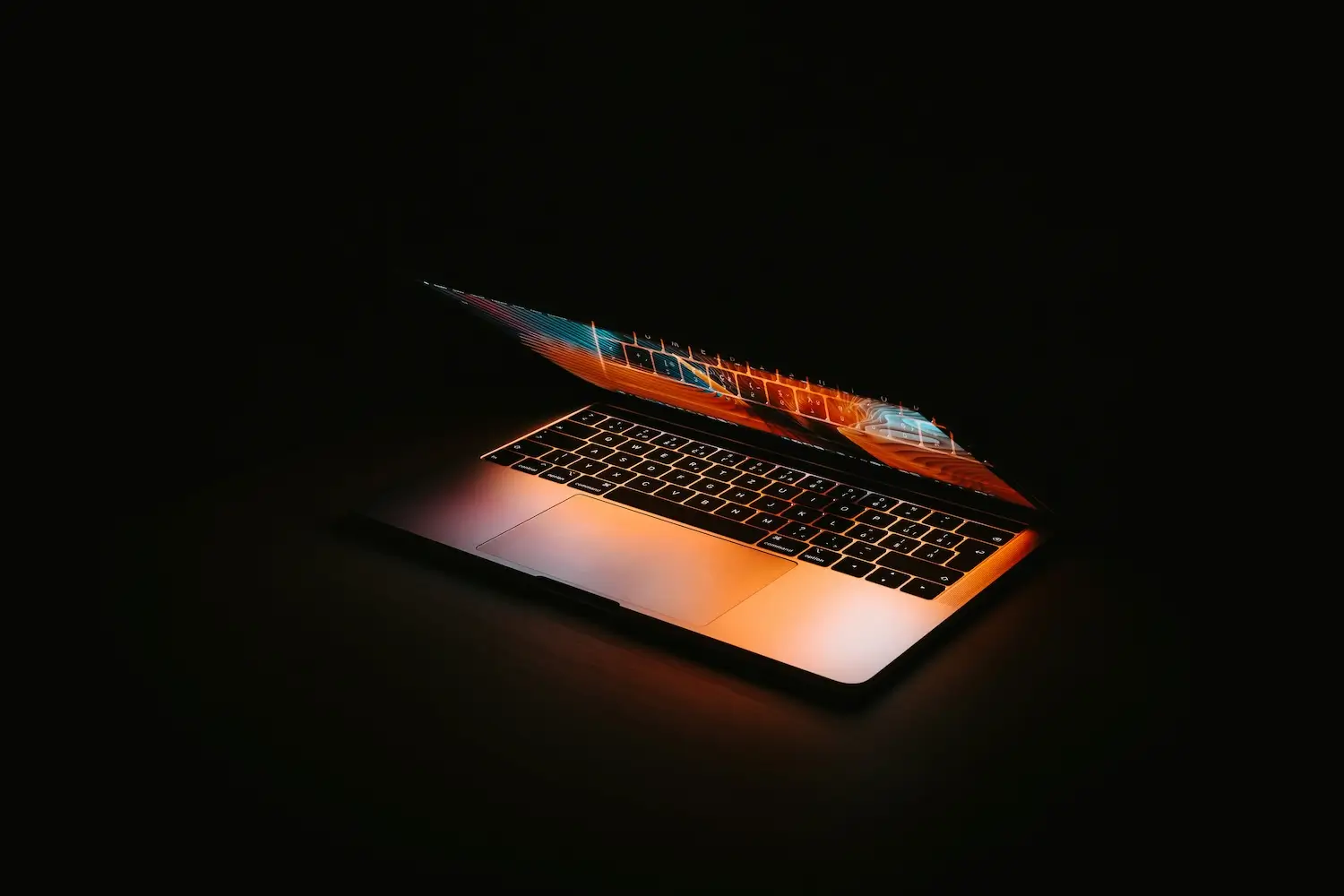 Halfopen laptop met oranje digitale gloed in donkere ruimte, symbool voor AI-technologie en automatisering.
